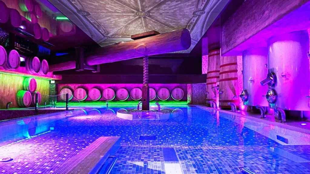 Spa con piscina iluminada en morado entre grandes depósitos de bodega