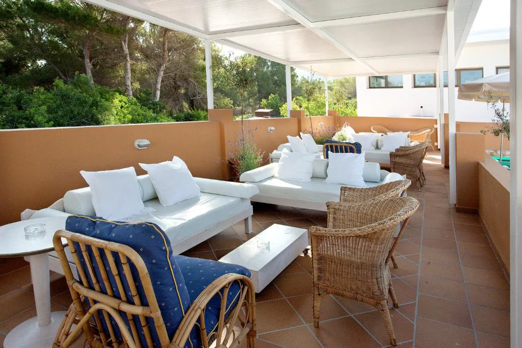 Terraza chill out con sofás blancos y sillones de mimbre bajo un porche, Hotel & Spa Entre Pinos