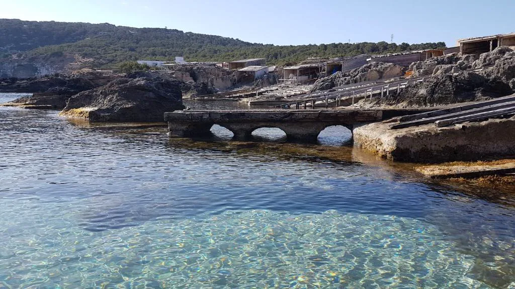 Varaderos tradicionales de madera junto al mar cristalino de Es Caló, cerca de Hotel & Spa Entre Pinos