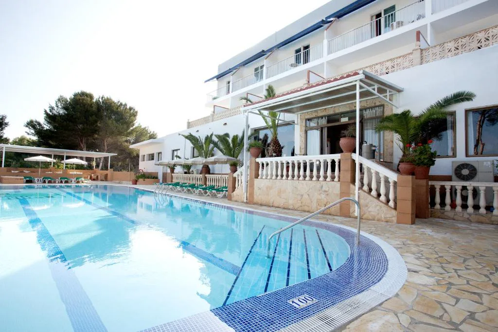 Piscina rodeada de tumbonas y palmeras junto al edificio del hotel, Hotel & Spa Entre Pinos, Es Caló, Formentera