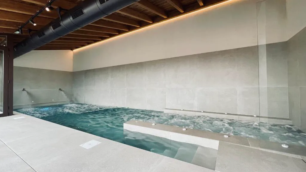 Piscina interior de hidromasaje con techo de madera vista en el Hotel SPA John Te Lo Busca