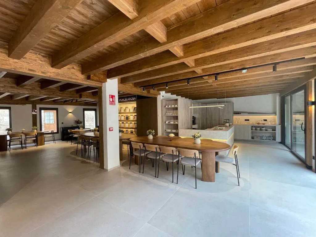 Comedor común con mesa larga de madera y cocina abierta