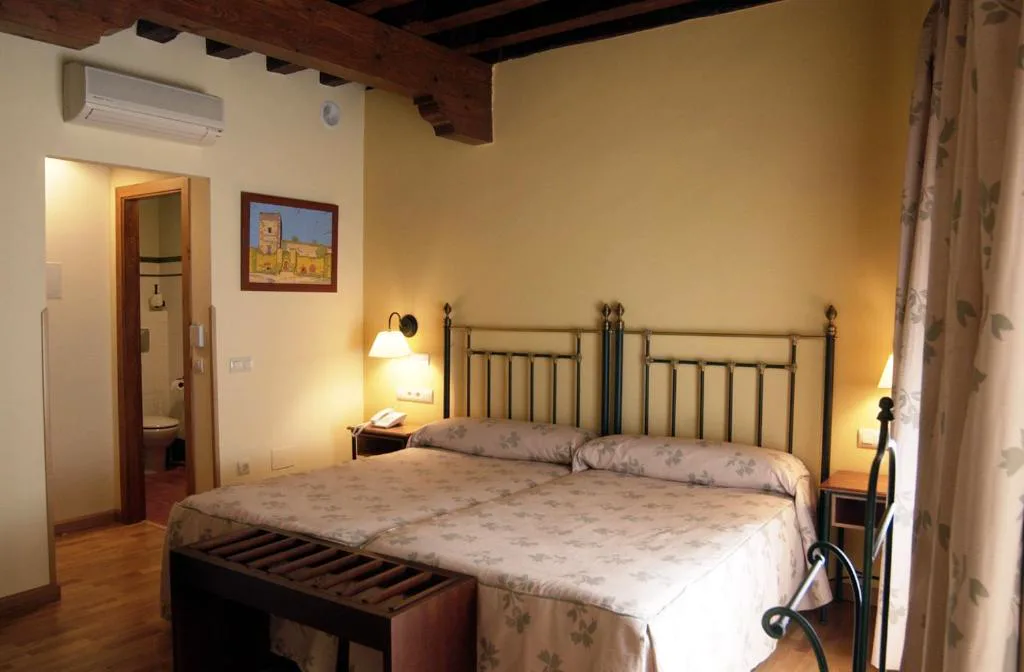 Habitación con vigas de madera y cabecero de forja