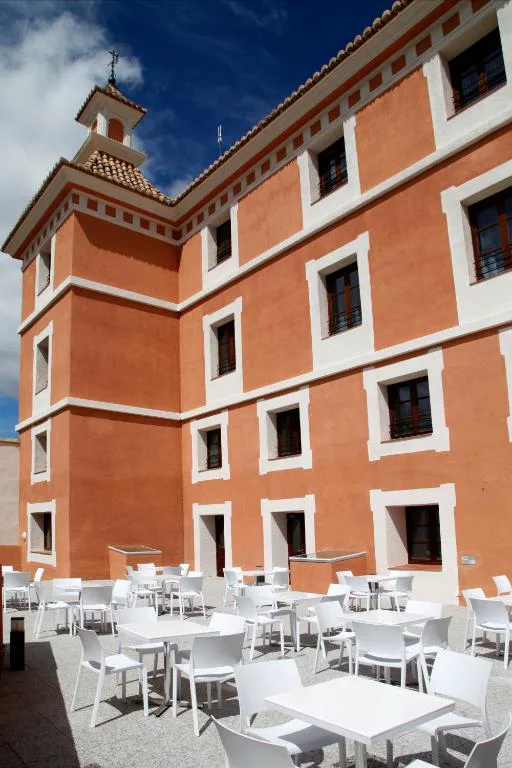 Fachada de ladrillo del hotel con terraza de mesas blancas