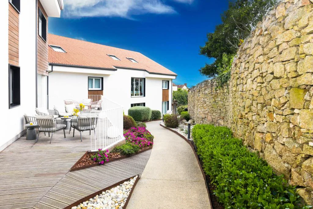 Jardín con muro de piedra tradicional gallega y hórreo al fondo, Hotel Spa Meiga do Mar