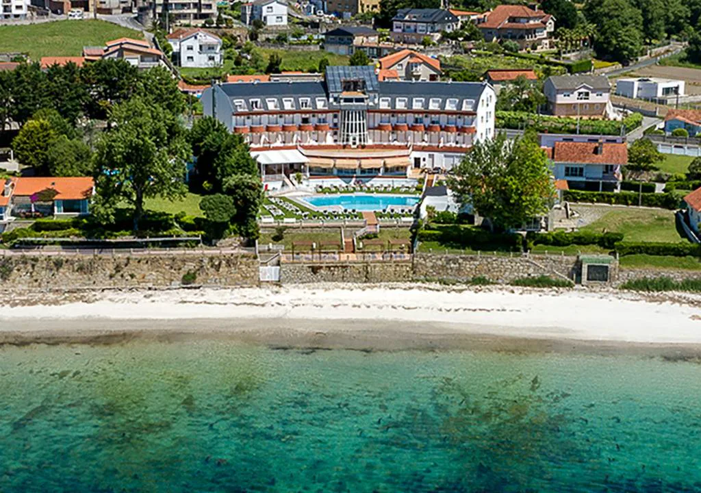 Vista aérea del hotel en primera línea de la playa de Nanín, con piscina y jardines
