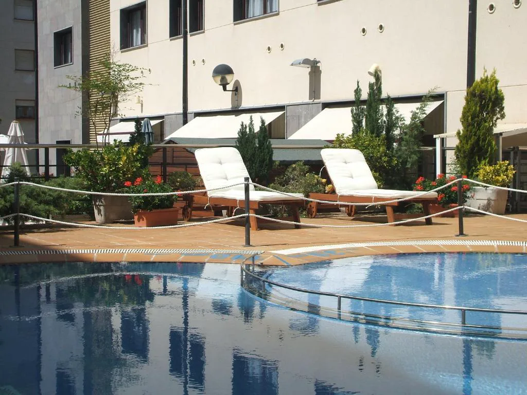 Piscina exterior con tumbonas blancas junto al hotel