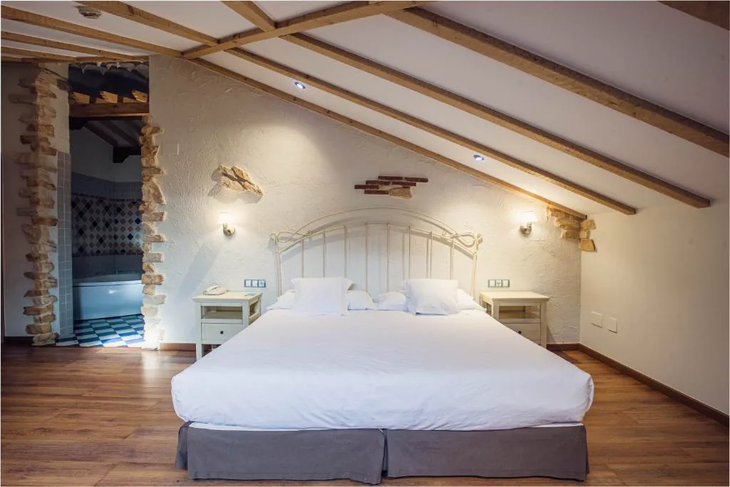 Habitación abuhardillada con cama blanca