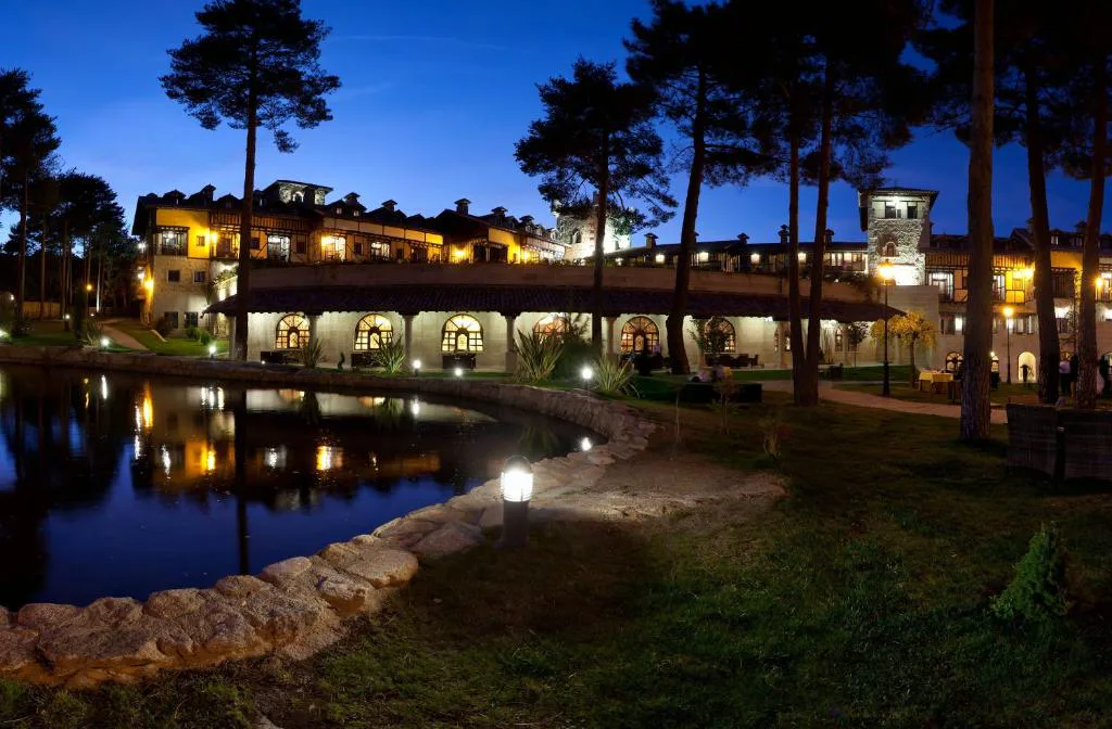 Hotel iluminado al anochecer junto a un estanque