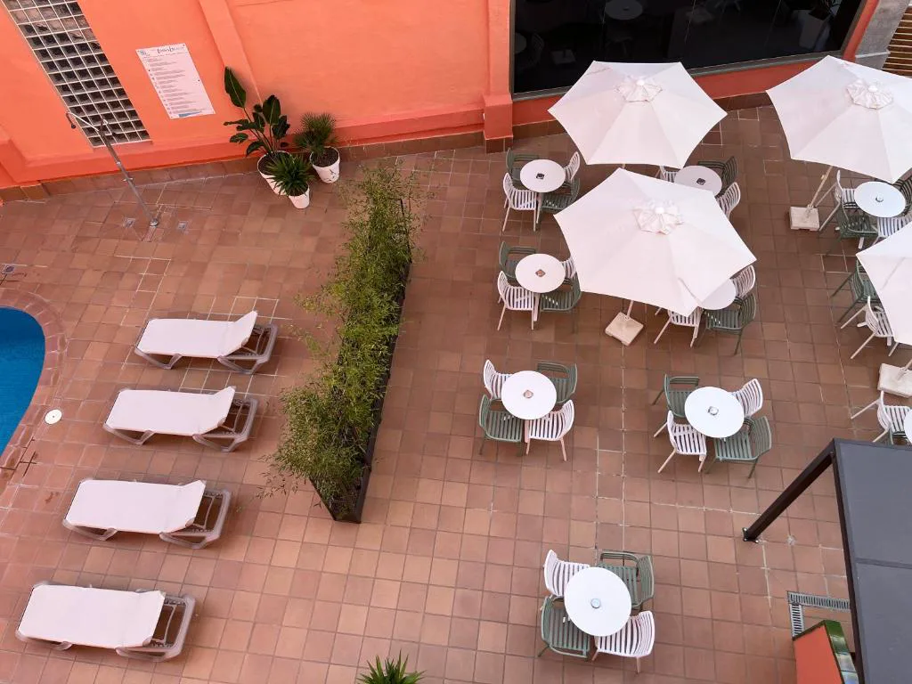Terraza con sombrillas blancas y sillas junto al hotel