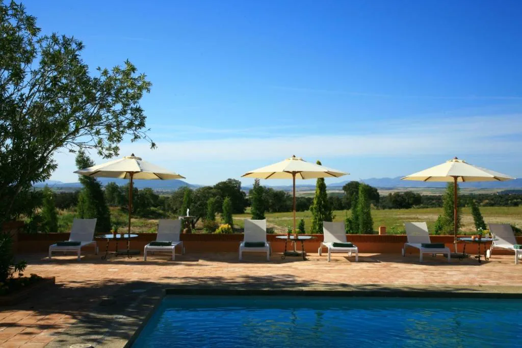Piscina exterior con sombrillas y un valle al fondo