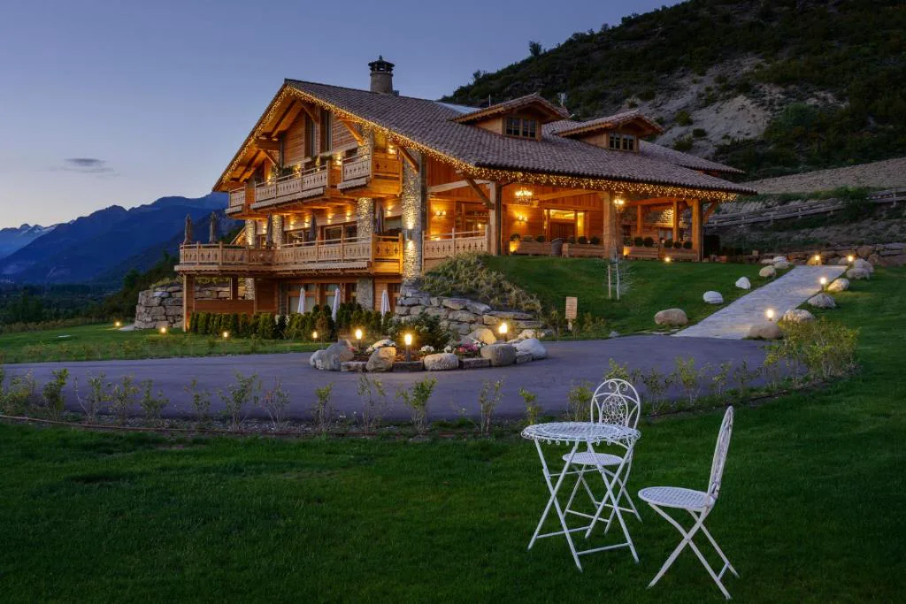 Hotel de madera y piedra con jardín y sillas blancas