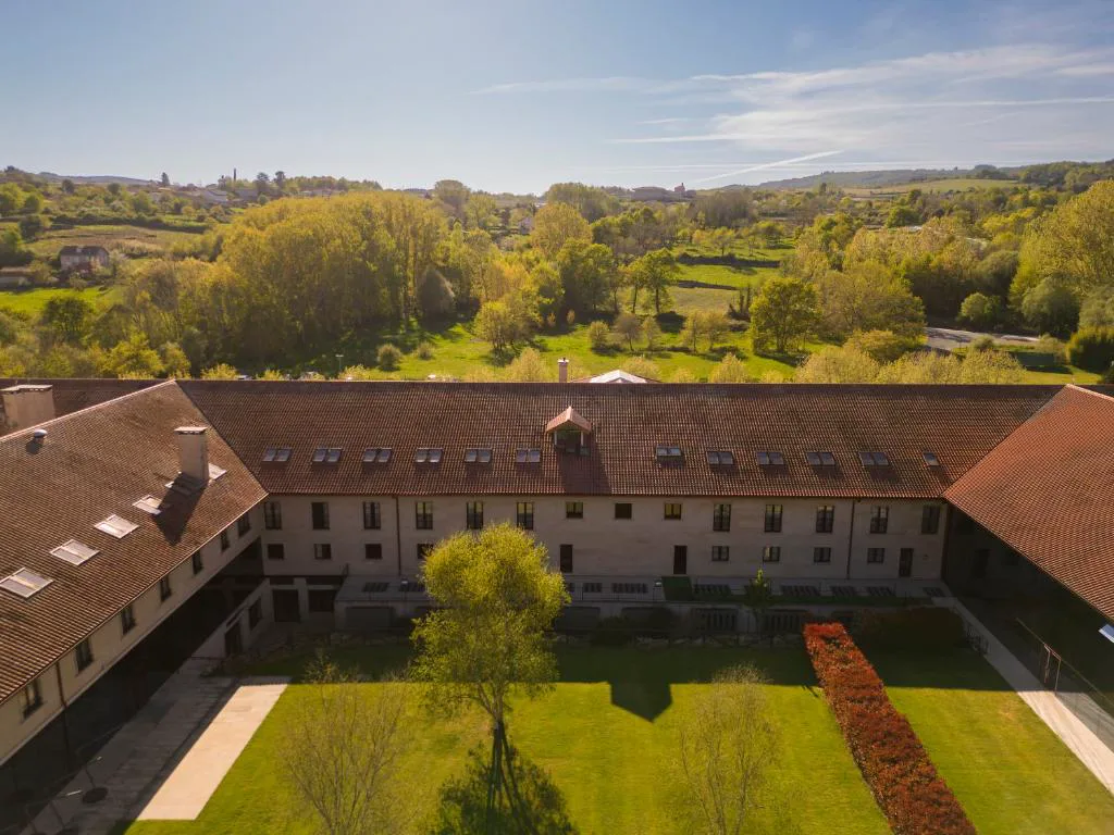 Vista aérea del edificio histórico del balneario rodeado de vegetación, IBERIK Augas Santas