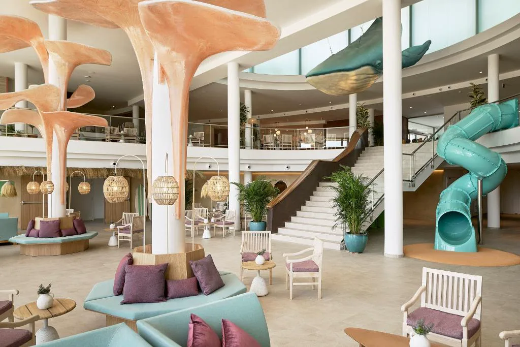 Lobby con escultura de ballena suspendida y tobogán decorativo, Iberostar Waves Gaviotas Park