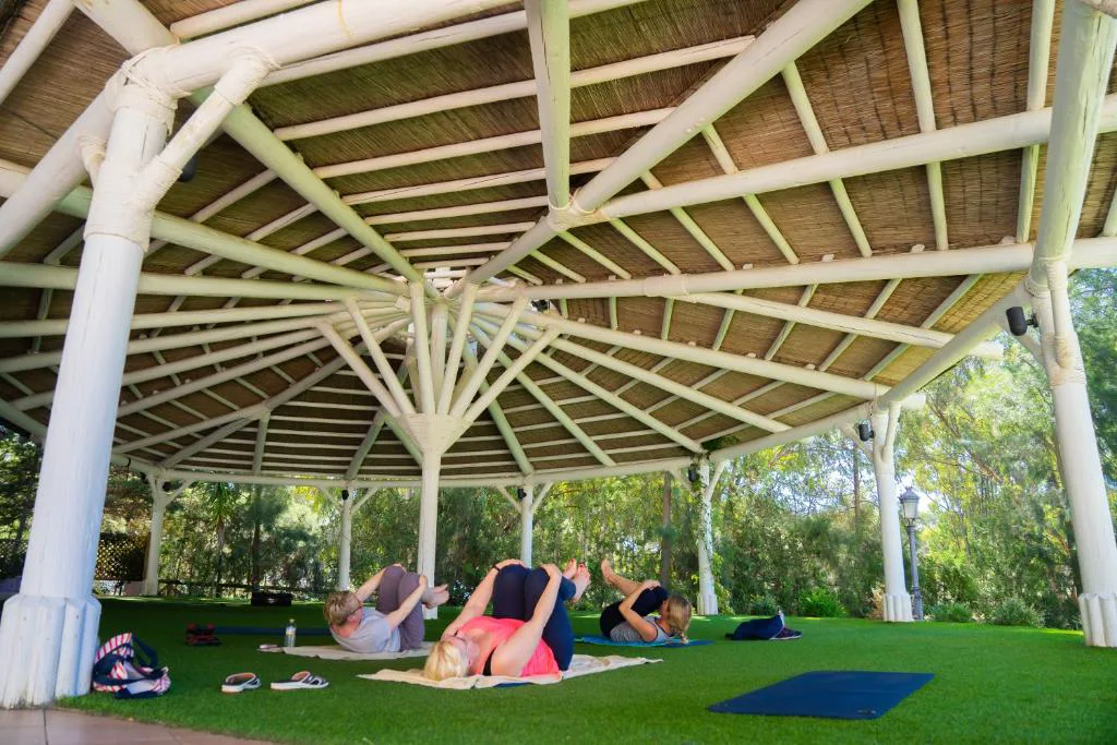 Pérgola blanca sobre césped con una clase de yoga