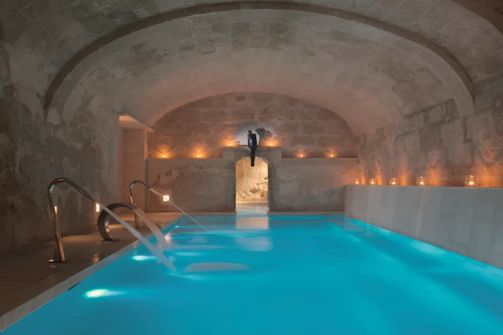 Piscina termal en cueva de piedra abovedada con velas, Jardí de Ses Bruixes