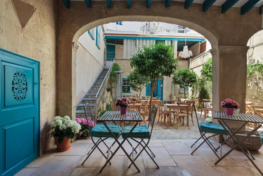 Patio interior con arco de piedra, chandeliers y mesas de hierro, Jardí de Ses Bruixes