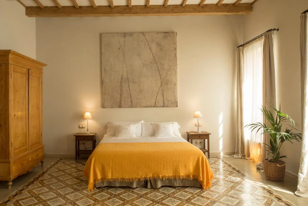 Dormitorio con colcha amarilla y armario de madera antiguo, Jardí de Ses Bruixes