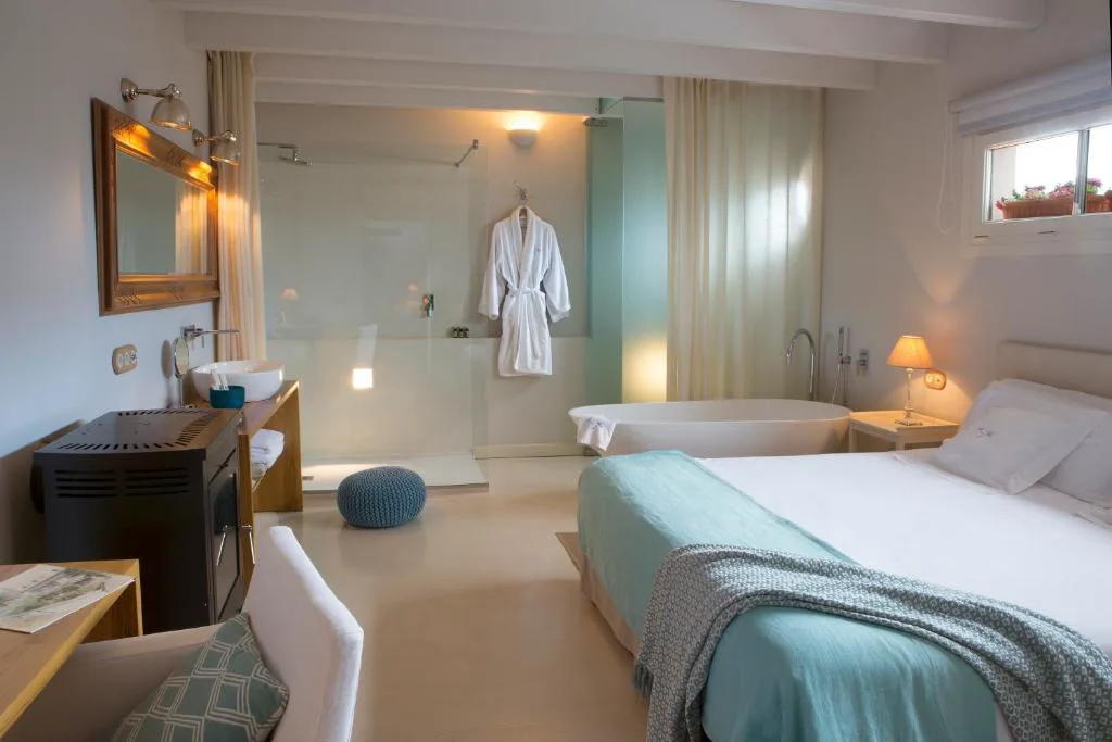 Dormitorio con bañera exenta junto a la cama y albornoz colgado, Jardí de Ses Bruixes