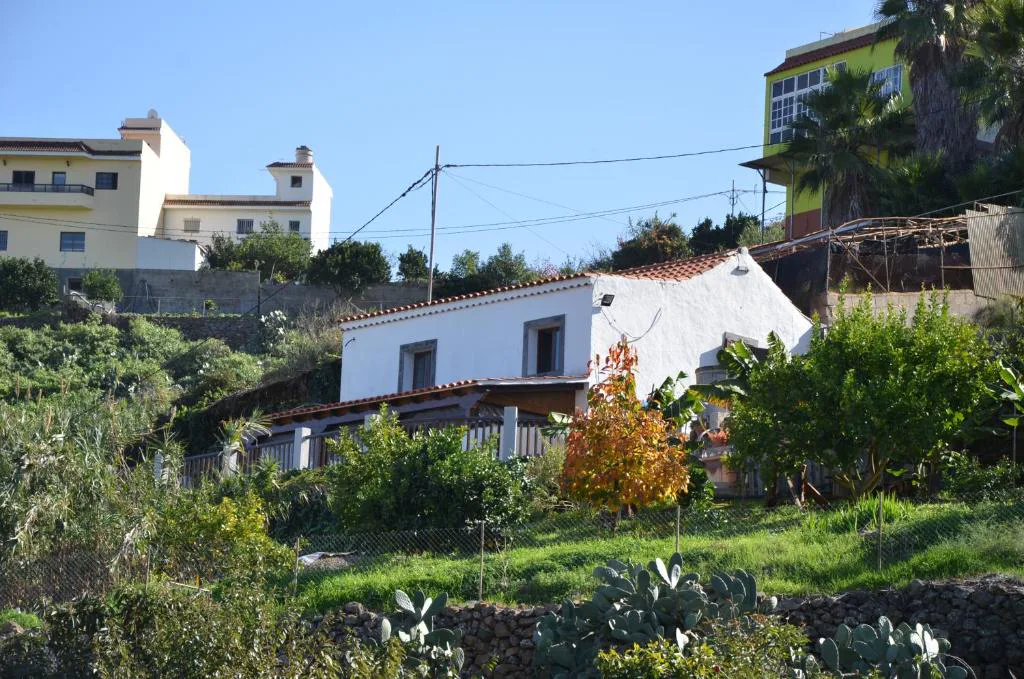 Fachada tradicional canaria blanca con tejado de teja entre plantas, La Berrera