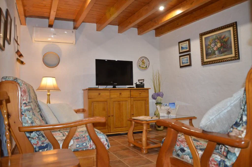 Salón con sillones de estampado floral y techo de vigas de madera, La Berrera