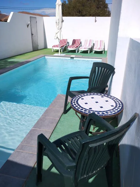 Piscina privada con tumbonas de rayas y mesa de mosaico, La Caldereta Casa Rural, en La Oliva, Fuerteventura