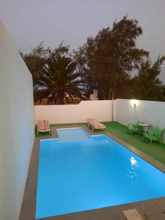Piscina privada iluminada al atardecer, con palmeras al fondo, La Caldereta Casa Rural