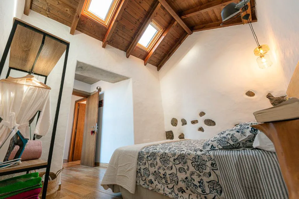 Dormitorio abuhardillado con ventanas de tejado y pared de piedra vista, La Candia y el Mar