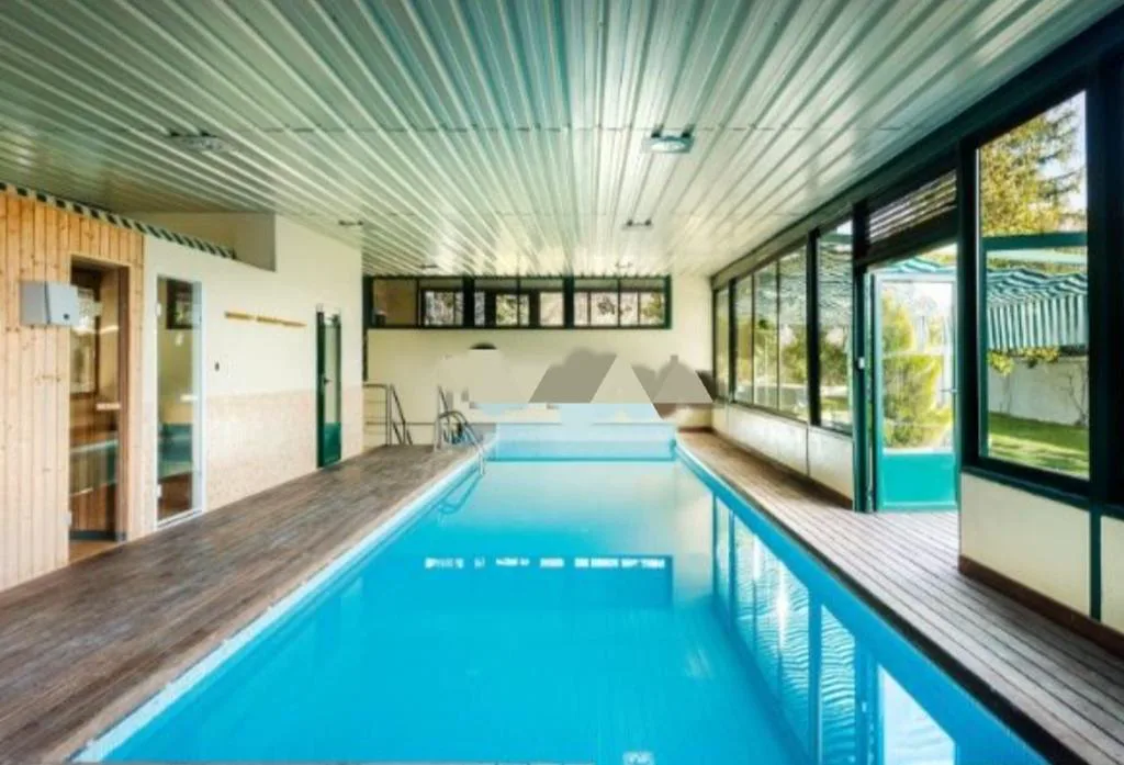 Piscina interior alargada con ventanales al jardín