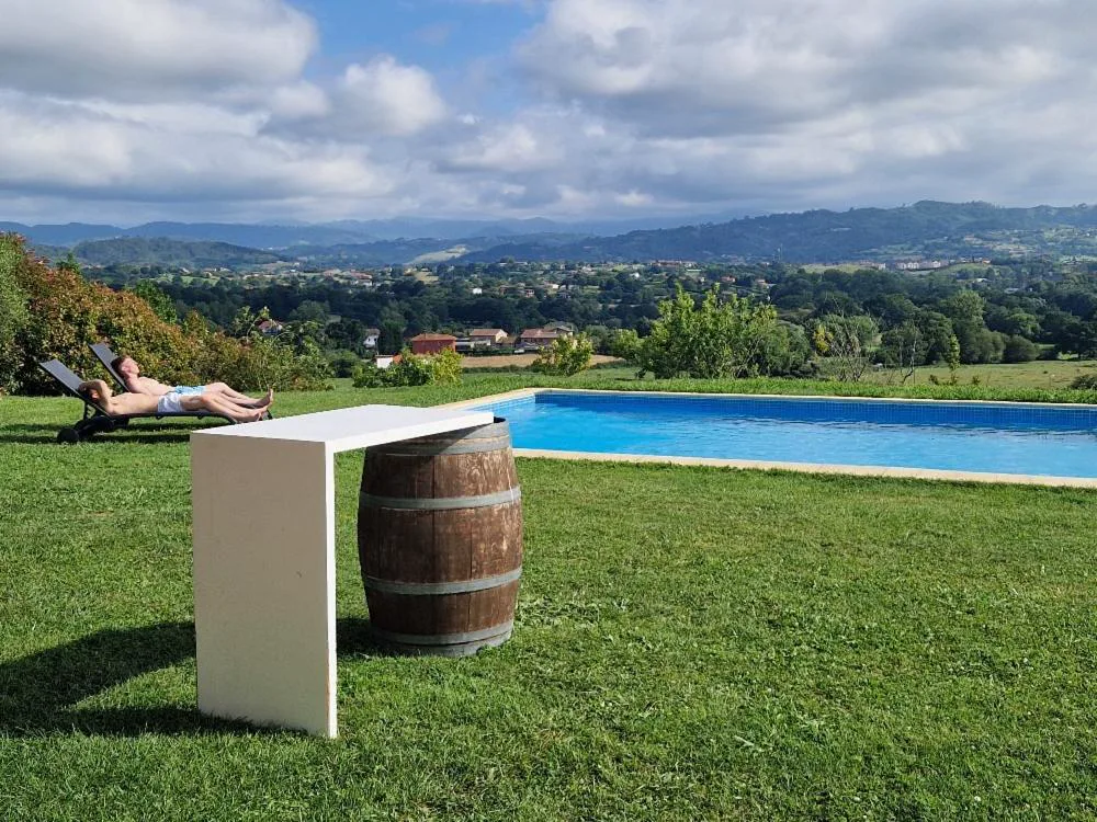 Piscina rodeada de césped con barril y mesa alta