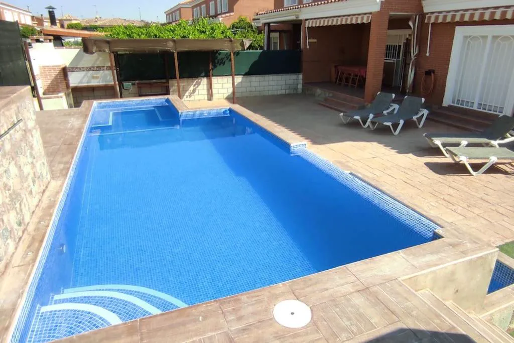 Piscina larga con tumbonas y pérgola en el jardín