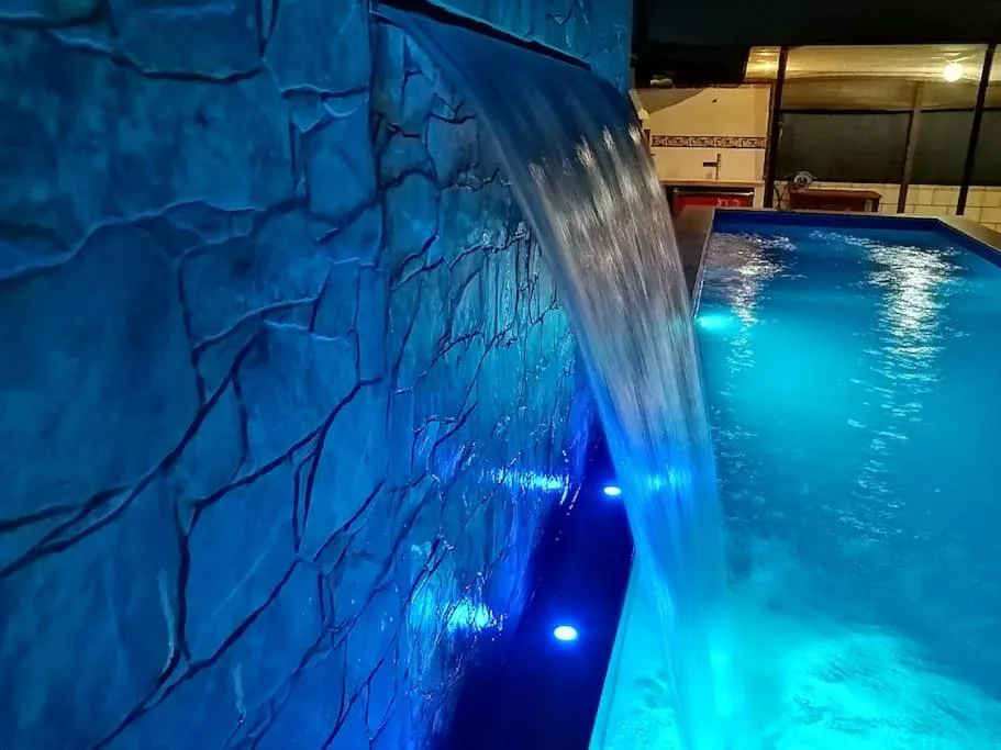 Piscina iluminada con cascada de roca