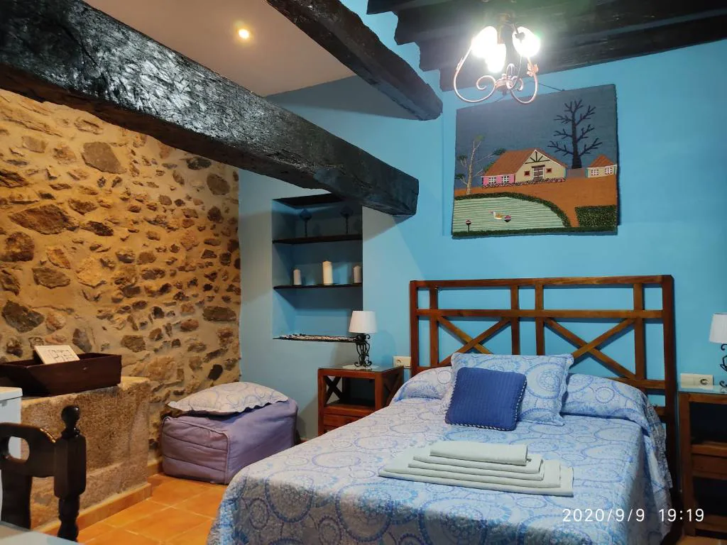 Habitación con muros de piedra y cabecero azul