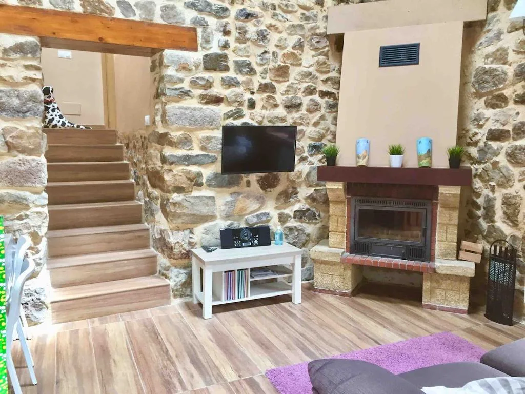 Salón con chimenea de piedra y escalera de madera