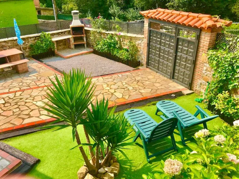 Patio empedrado con barbacoa y tumbonas rodeado de plantas