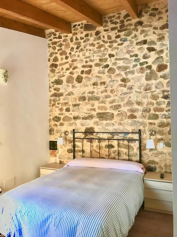 Dormitorio con muro de piedra y cabecero de forja