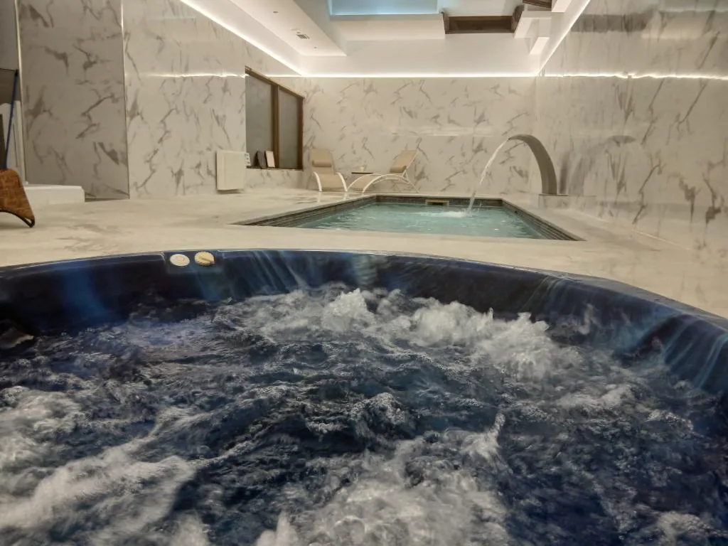 Jacuzzi en la sala del spa, con una piscina pequeña al fondo y paredes de mármol claro