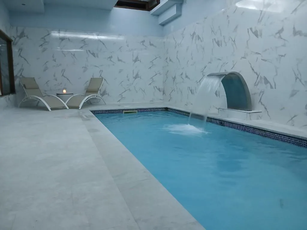 Piscina interior de paredes blancas con cascada y tumbonas