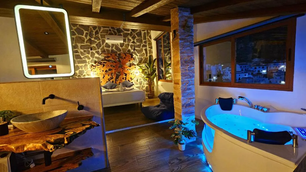 Habitación de piedra con bañera de hidromasaje y vigas de madera