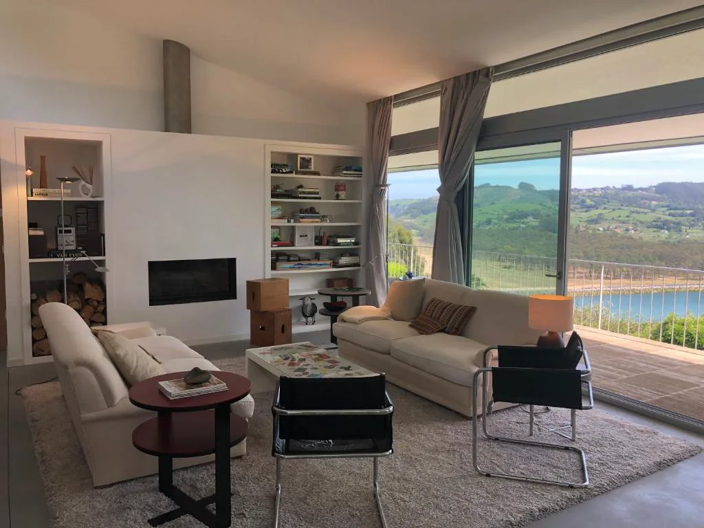 Salón con grandes ventanales sobre la ría y sillones claros