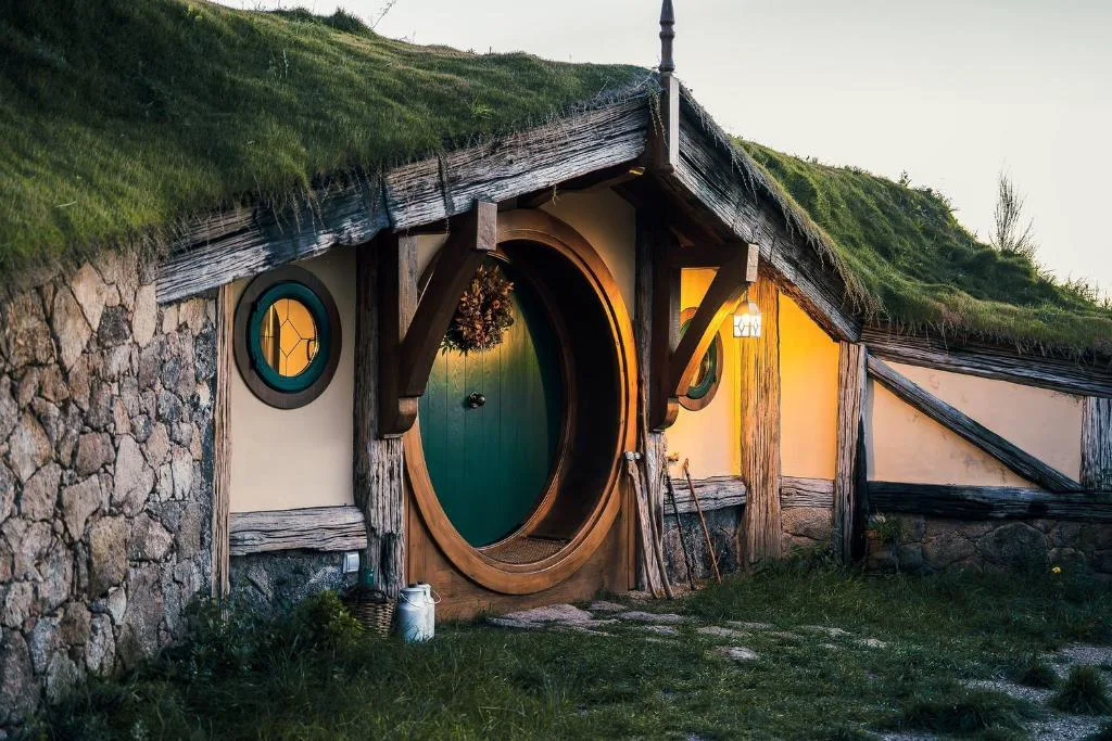 Casa hobbit con puerta redonda excavada en una ladera de hierba