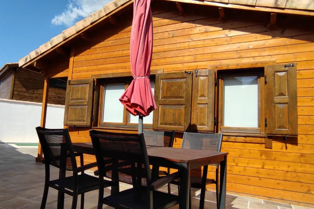 Cabaña de madera con terraza y mesa exterior