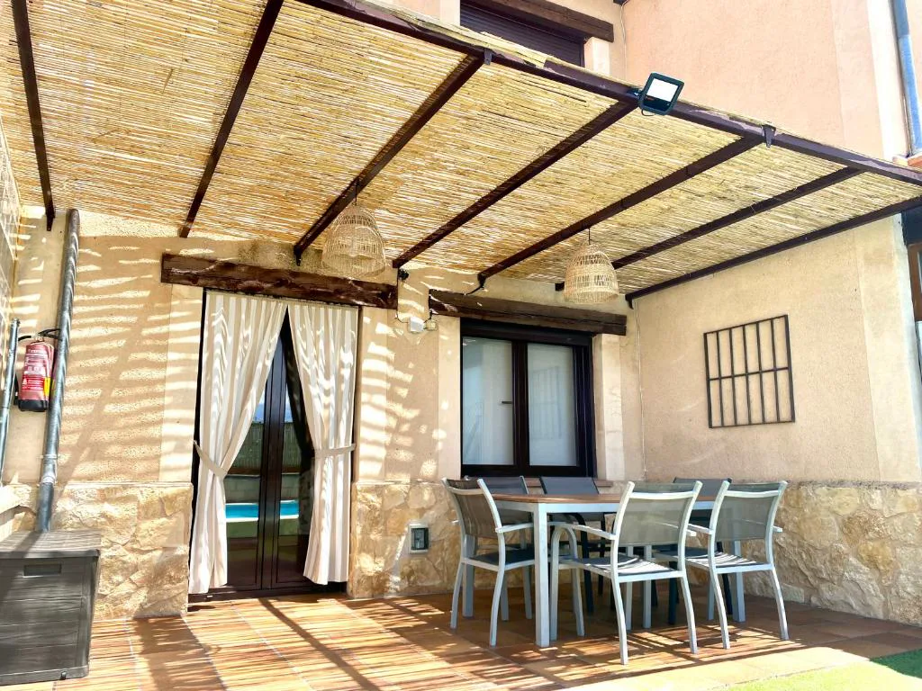 Porche con mesa, sillas y cañizo bajo un arco de piedra