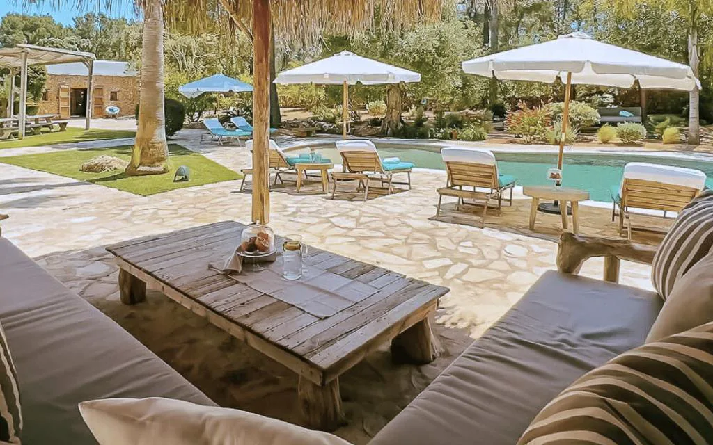 Porche con sofás y mesa de madera junto a la piscina bajo techo de cañizo, La Finca Agroturismo Can Bet