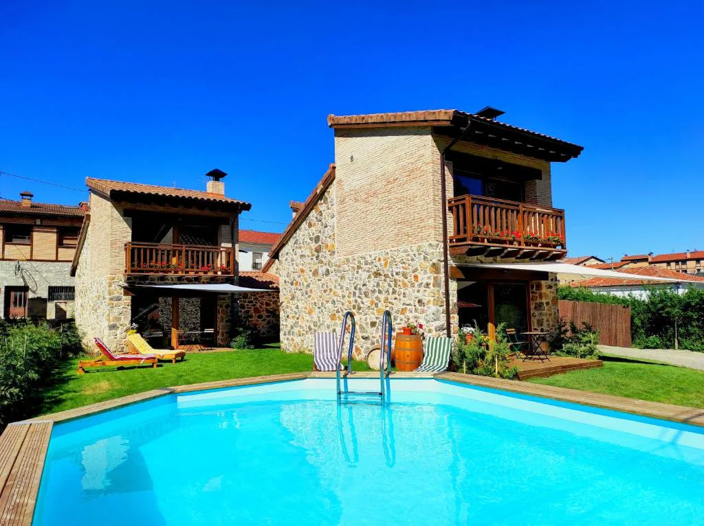 Casa de piedra y madera con piscina azul en primer plano
