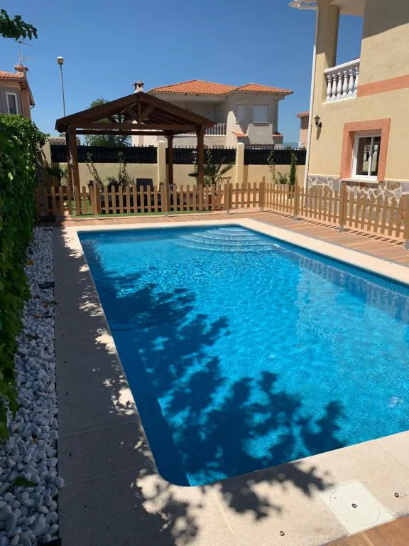Piscina rodeada de un cenador de madera junto a una casa