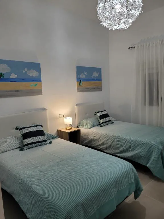 Dormitorio moderno con lámpara de araña floral y cuadros marineros, La Kasita