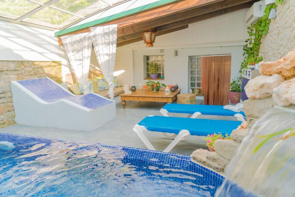 Patio con piscina y cascada rodeado de tumbonas