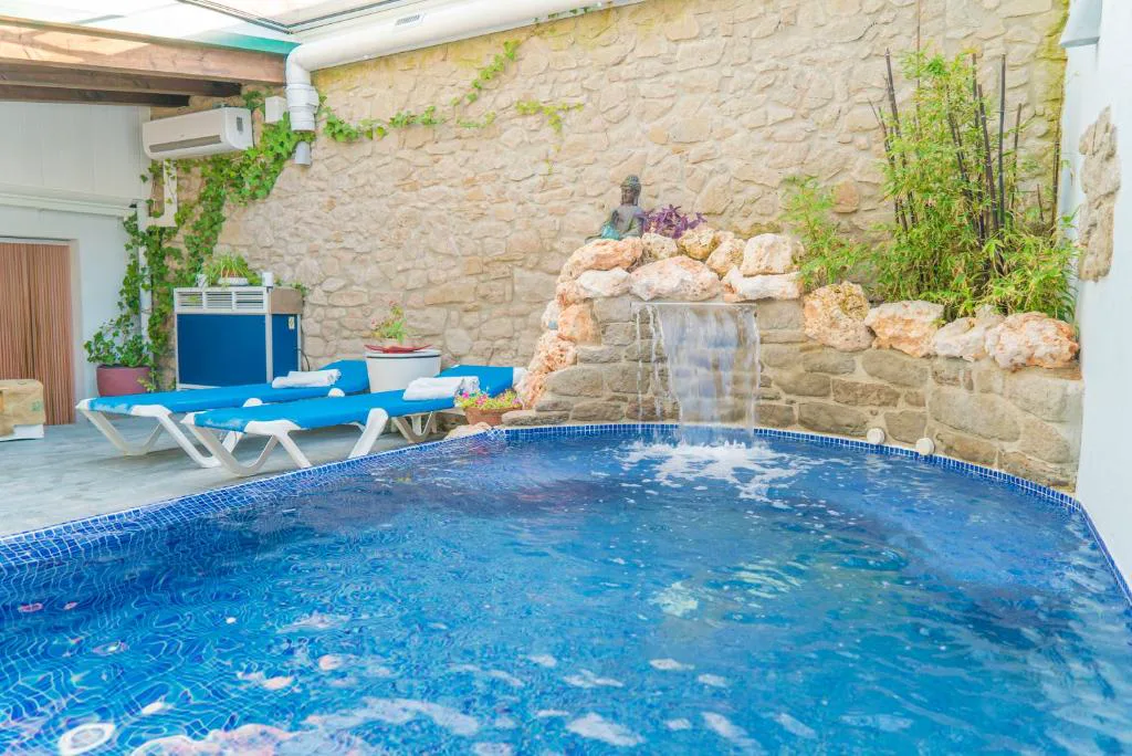 Piscina con cascada y tumbonas azules