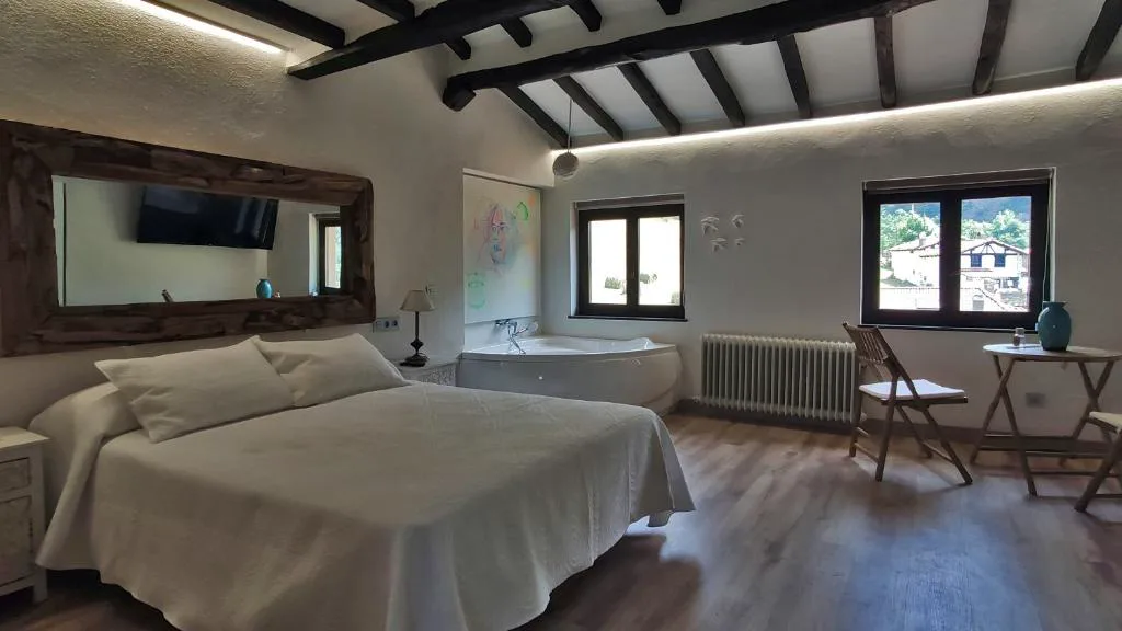 Habitación con cama doble, bañera redonda y vigas oscuras
